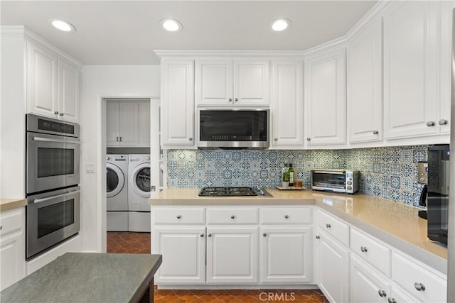 kitchen with white cabinets, appliances with stainless steel finishes, separate washer and dryer, and tasteful backsplash