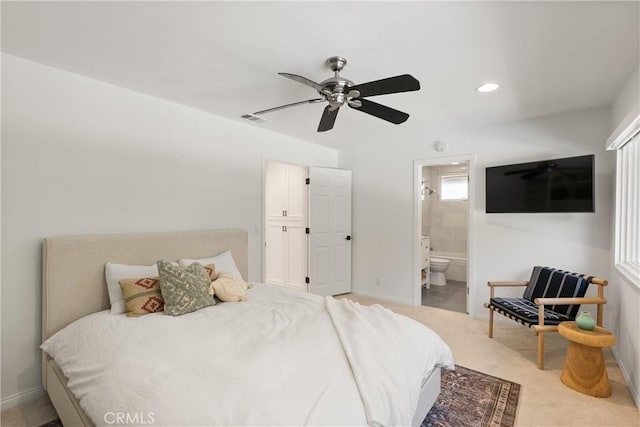 bedroom featuring light carpet, ceiling fan, and ensuite bath