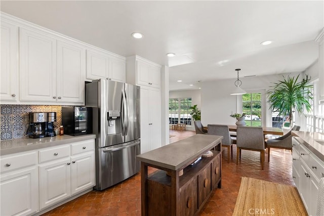 kitchen featuring stainless steel fridge, pendant lighting, white cabinets, and backsplash