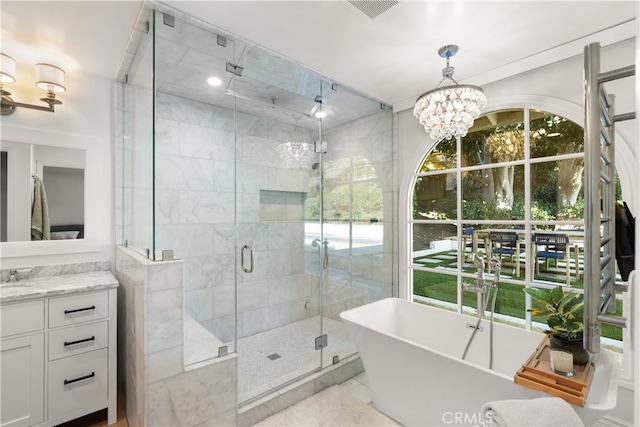 bathroom with vanity, an inviting chandelier, and shower with separate bathtub