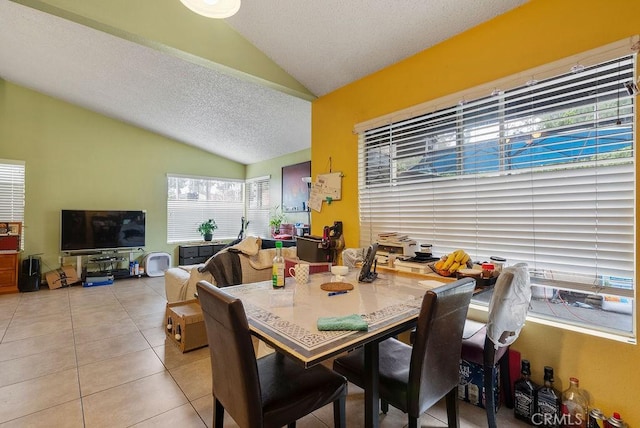 dining area featuring light tile patterned floors, vaulted ceiling, and a textured ceiling