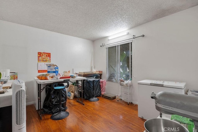 office featuring washer / clothes dryer, hardwood / wood-style flooring, and a textured ceiling