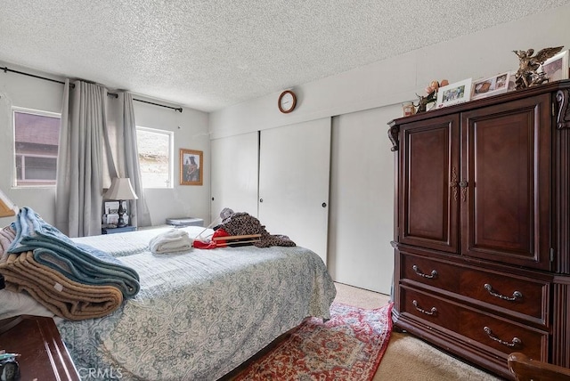 carpeted bedroom with a closet and a textured ceiling