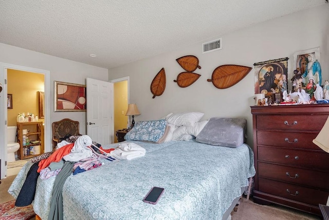 carpeted bedroom featuring ensuite bath and a textured ceiling