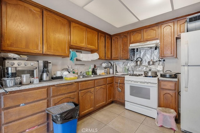 kitchen with light tile patterned floors, white appliances, and sink