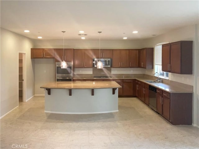kitchen featuring a sink, a breakfast bar area, a center island, stainless steel appliances, and decorative light fixtures