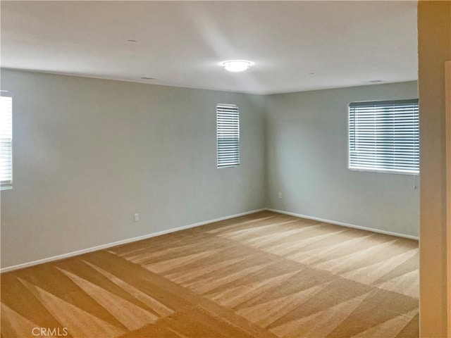 spare room featuring baseboards and light carpet