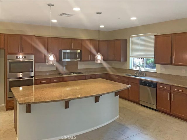 kitchen with a kitchen island, a breakfast bar, light stone counters, a sink, and stainless steel appliances
