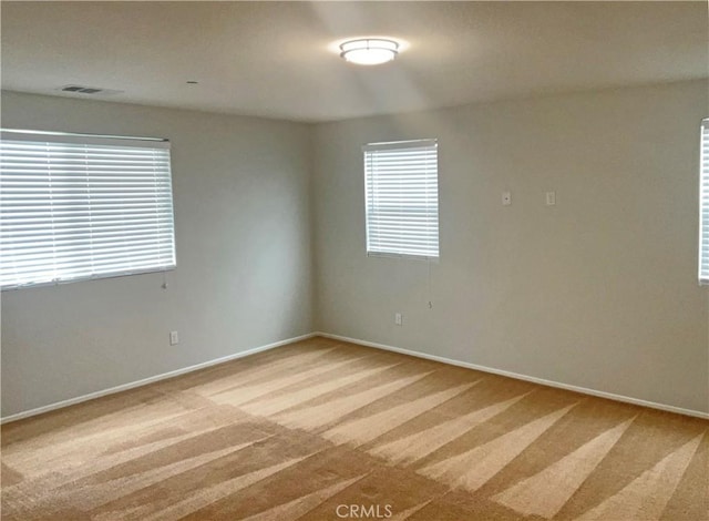 unfurnished room featuring baseboards, visible vents, and light carpet