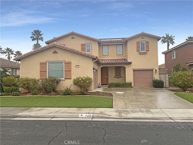 mediterranean / spanish-style house featuring a tiled roof, stucco siding, concrete driveway, and a garage