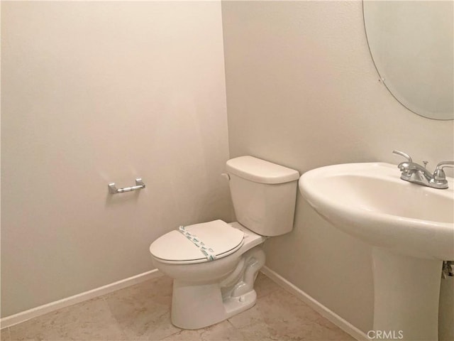 half bathroom featuring a sink, baseboards, tile patterned flooring, and toilet
