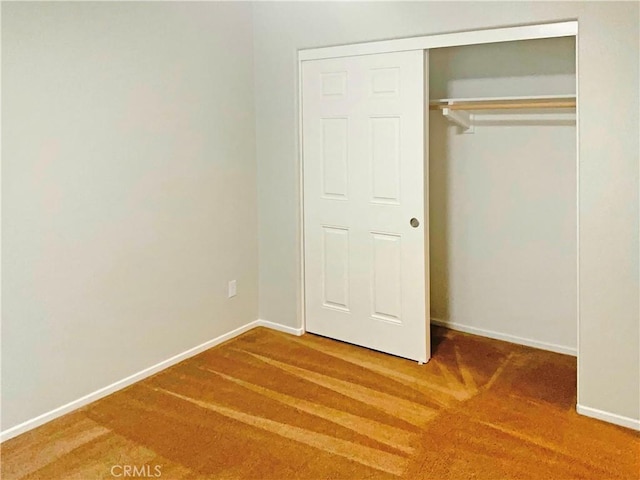 unfurnished bedroom with carpet floors, baseboards, and a closet
