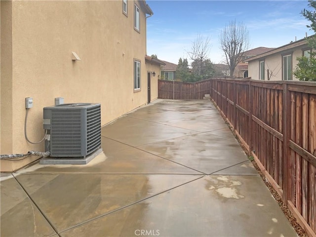 view of property exterior featuring cooling unit, a fenced backyard, a patio area, and stucco siding