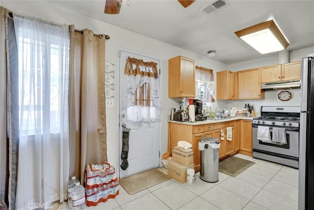 kitchen featuring light brown cabinetry, light tile patterned floors, stainless steel range with gas stovetop, and ceiling fan