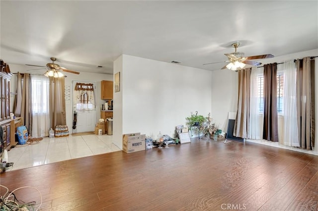 unfurnished living room featuring a wealth of natural light, ceiling fan, and light wood-type flooring