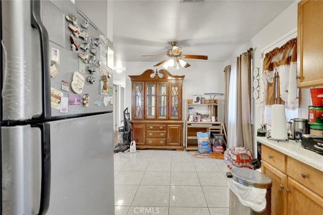 kitchen with ceiling fan, light tile patterned floors, and stainless steel refrigerator