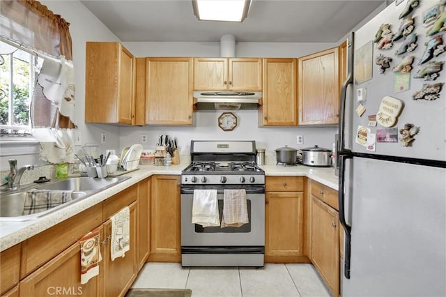 kitchen featuring sink, fridge, stainless steel range with gas stovetop, and light tile patterned flooring