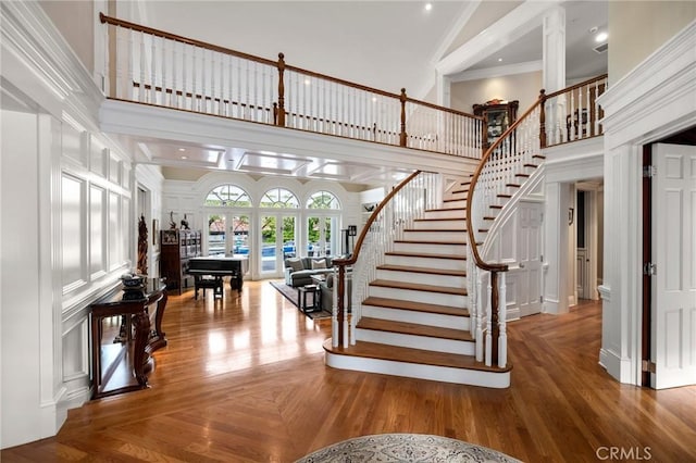 stairs with french doors, a high ceiling, crown molding, and a decorative wall