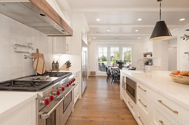 kitchen with light countertops, appliances with stainless steel finishes, hanging light fixtures, and white cabinetry