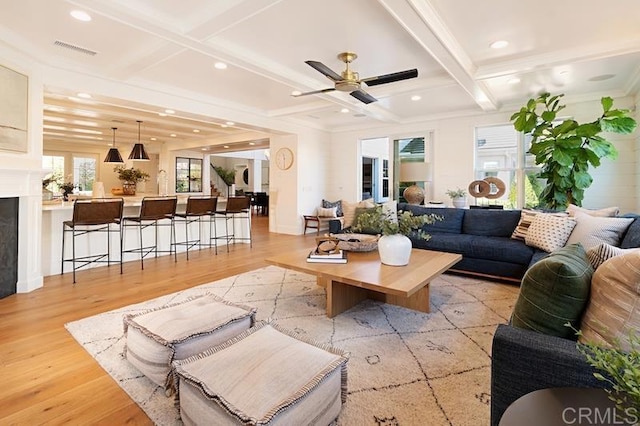 living room with light wood finished floors, visible vents, and coffered ceiling