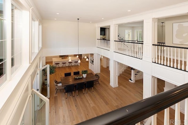 interior space featuring light wood-type flooring, a decorative wall, crown molding, and recessed lighting