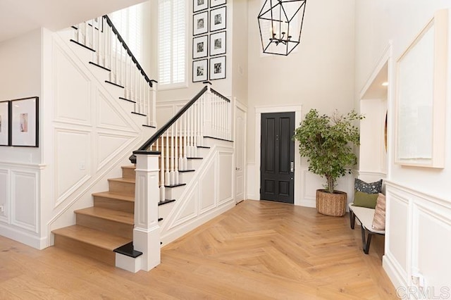 foyer entrance with a decorative wall, a towering ceiling, and an inviting chandelier