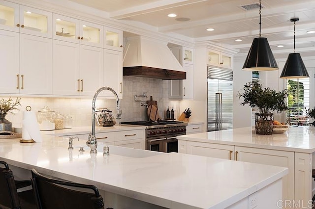 kitchen featuring a spacious island, visible vents, custom exhaust hood, high end appliances, and glass insert cabinets