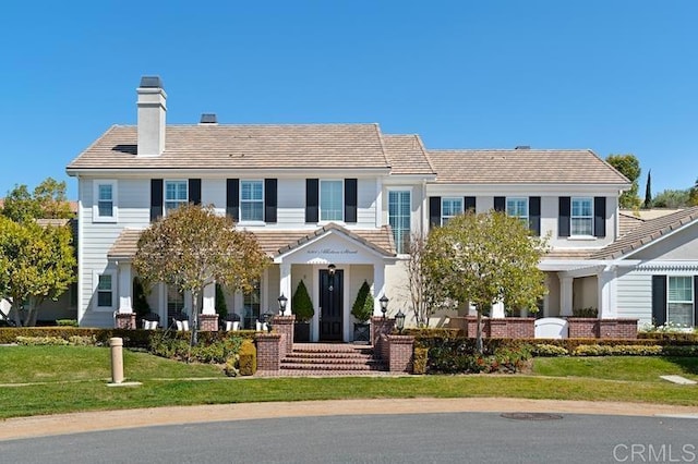 view of front facade with a front yard and a tiled roof