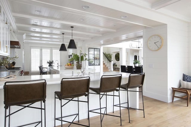 kitchen with light countertops, light wood-type flooring, a kitchen bar, and white cabinets