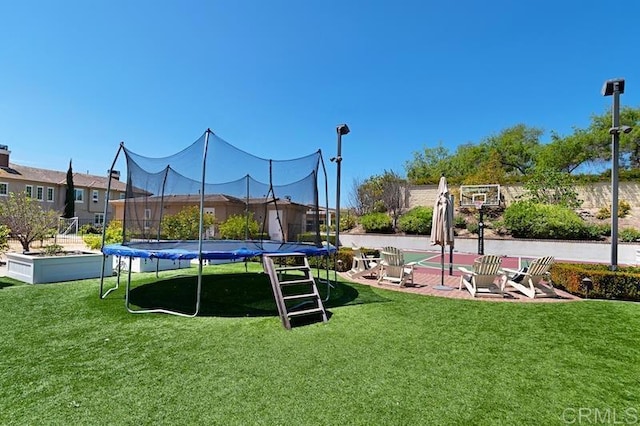 view of property's community with a trampoline and a yard