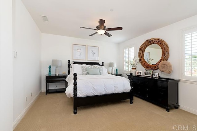 bedroom featuring baseboards, multiple windows, visible vents, and light colored carpet