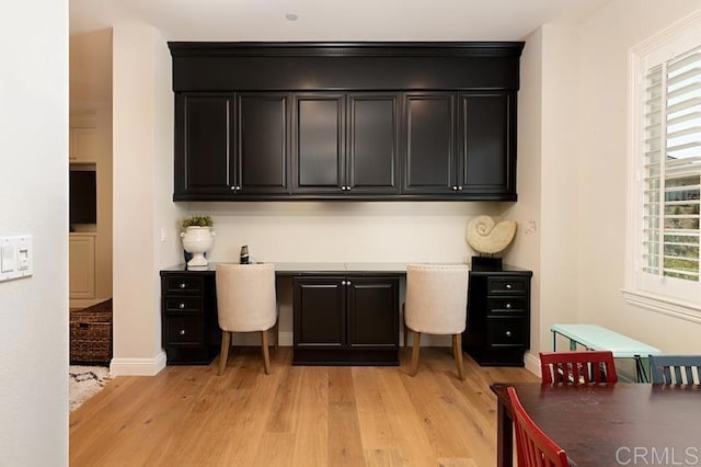 office area featuring built in study area, light wood-style flooring, and baseboards