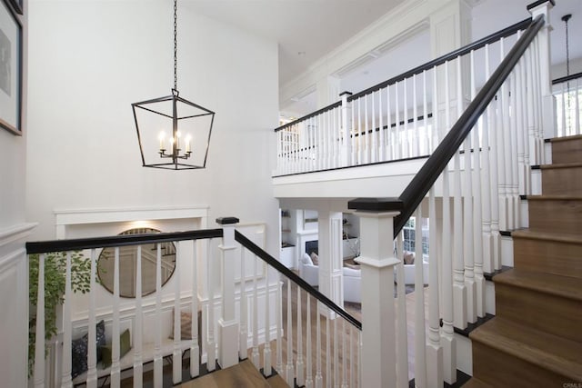 stairs featuring a chandelier, wood finished floors, and a towering ceiling