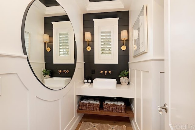 bathroom with crown molding, a sink, and wood finished floors