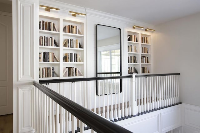 hall with ornamental molding, wainscoting, and a decorative wall