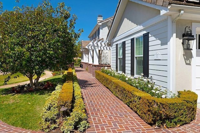 view of side of property with a chimney, a lawn, and a pergola