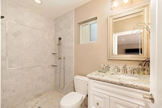 bathroom featuring tiled shower, vanity, and toilet