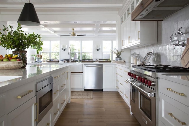 kitchen with decorative light fixtures, stainless steel appliances, tasteful backsplash, white cabinets, and under cabinet range hood