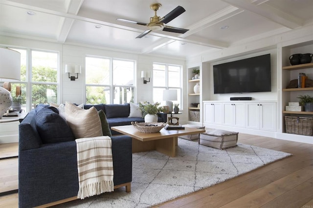 living room featuring built in features, beam ceiling, light wood-style floors, a ceiling fan, and coffered ceiling