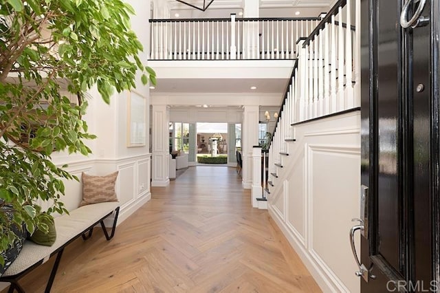 entryway featuring a decorative wall, a towering ceiling, and stairs