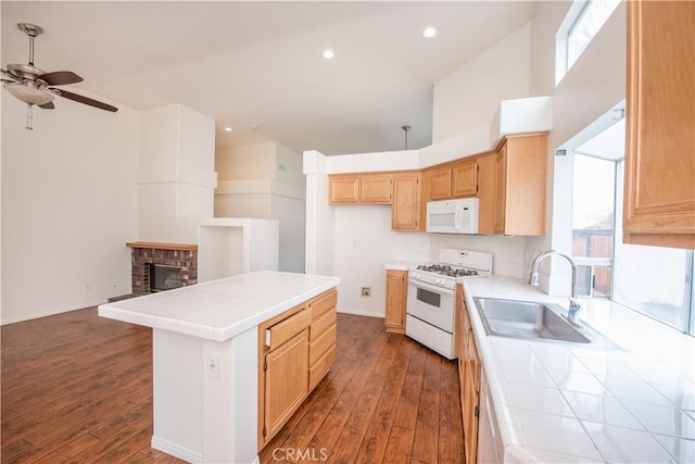 kitchen with sink, a center island, tile counters, hardwood / wood-style flooring, and white appliances