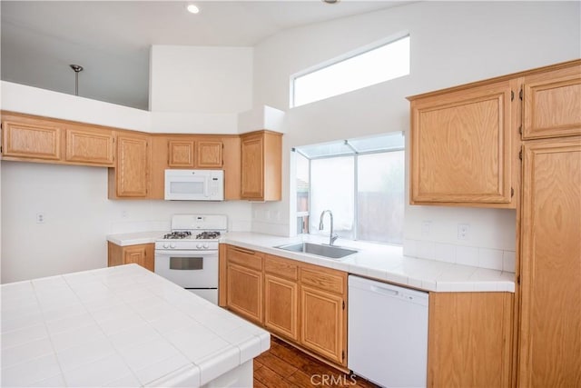 kitchen featuring dark wood-type flooring, sink, tile countertops, high vaulted ceiling, and white appliances