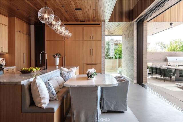 dining room with sink, a notable chandelier, wooden walls, and wooden ceiling