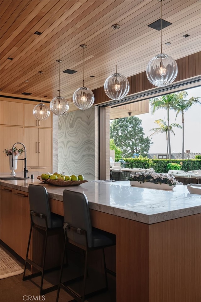 kitchen featuring wood ceiling, decorative light fixtures, sink, and light brown cabinets