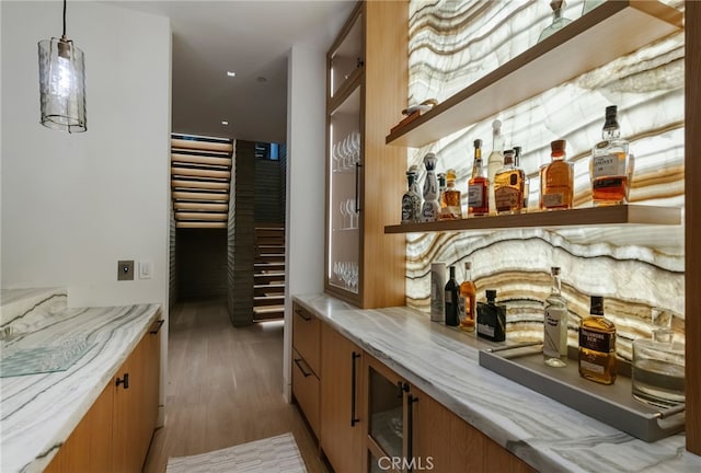 bar with light stone counters, hanging light fixtures, and dark hardwood / wood-style floors