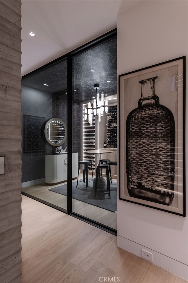 wine area featuring wood-type flooring and a chandelier
