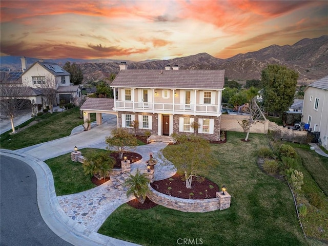 view of front facade with a balcony, a yard, and a mountain view