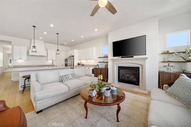 living room with sink, ceiling fan, and light wood-type flooring