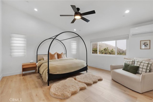 bedroom featuring light hardwood / wood-style flooring, a wall unit AC, and ceiling fan