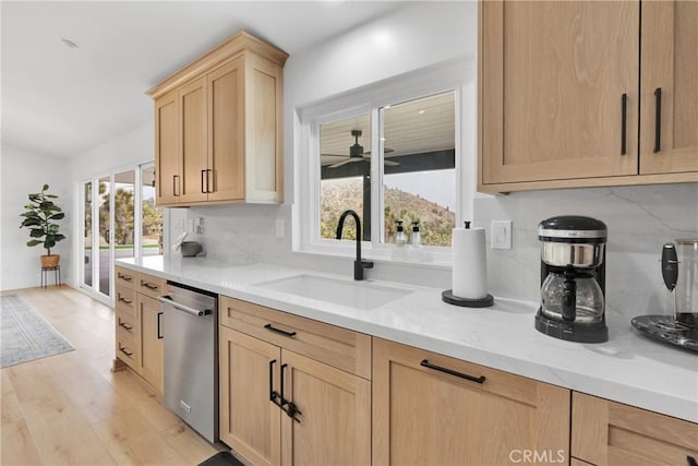 kitchen featuring light brown cabinetry, sink, stainless steel dishwasher, light stone countertops, and decorative backsplash